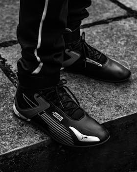Stylish black sneakers on a textured urban surface, emphasizing modern fashion and street style.
