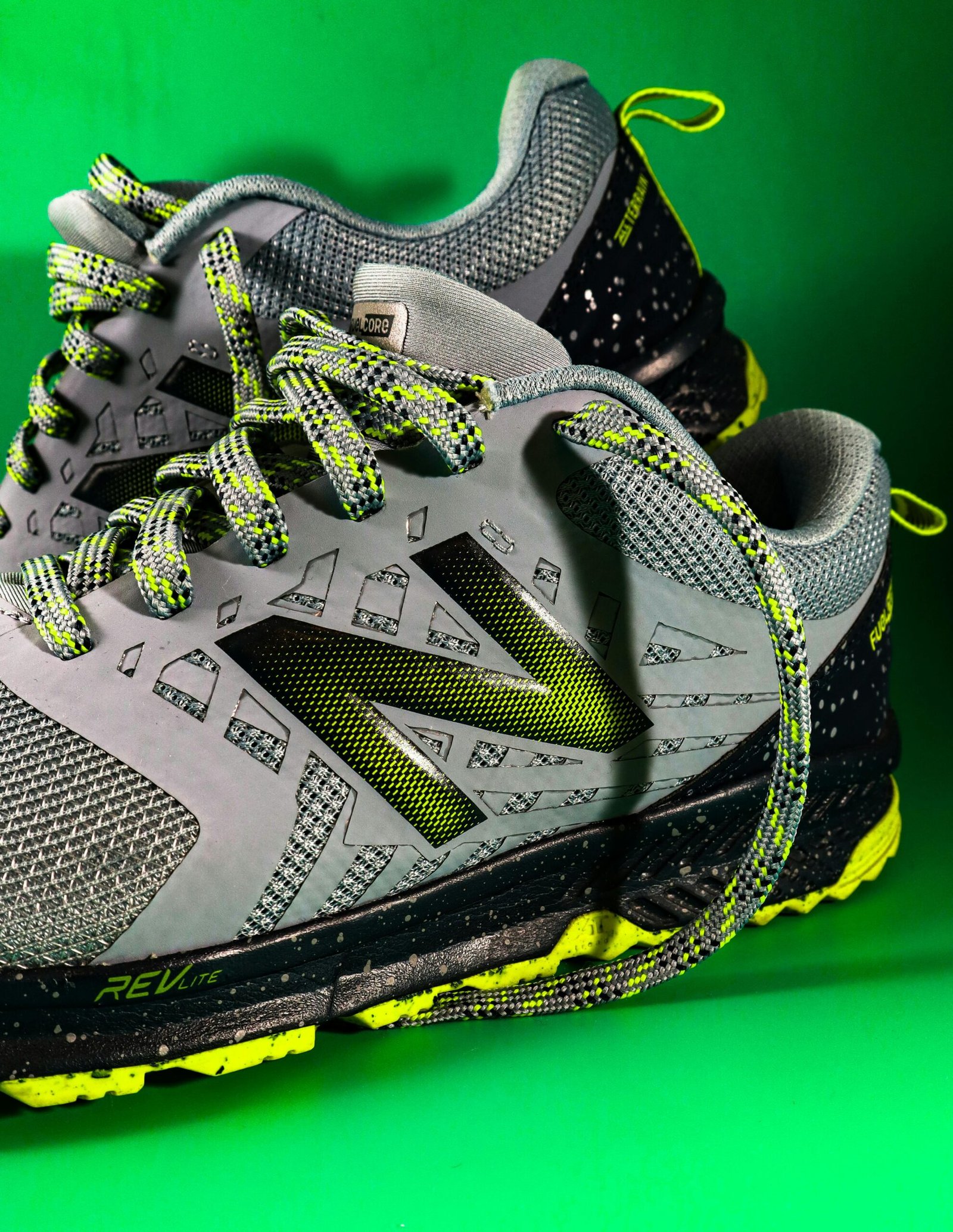 Close-up of trendy New Balance running shoes with vibrant design on a green background.
