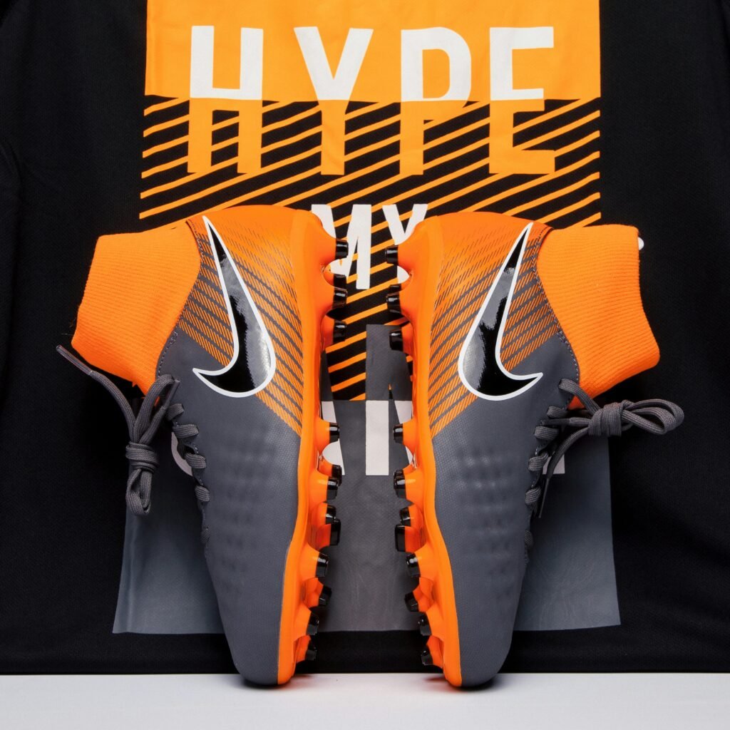 Nike Shoes: Redefining Performance, Style, and Innovation Close-up of gray and orange soccer cleats displayed against a bold background, ideal for fashion and sports enthusiasts.