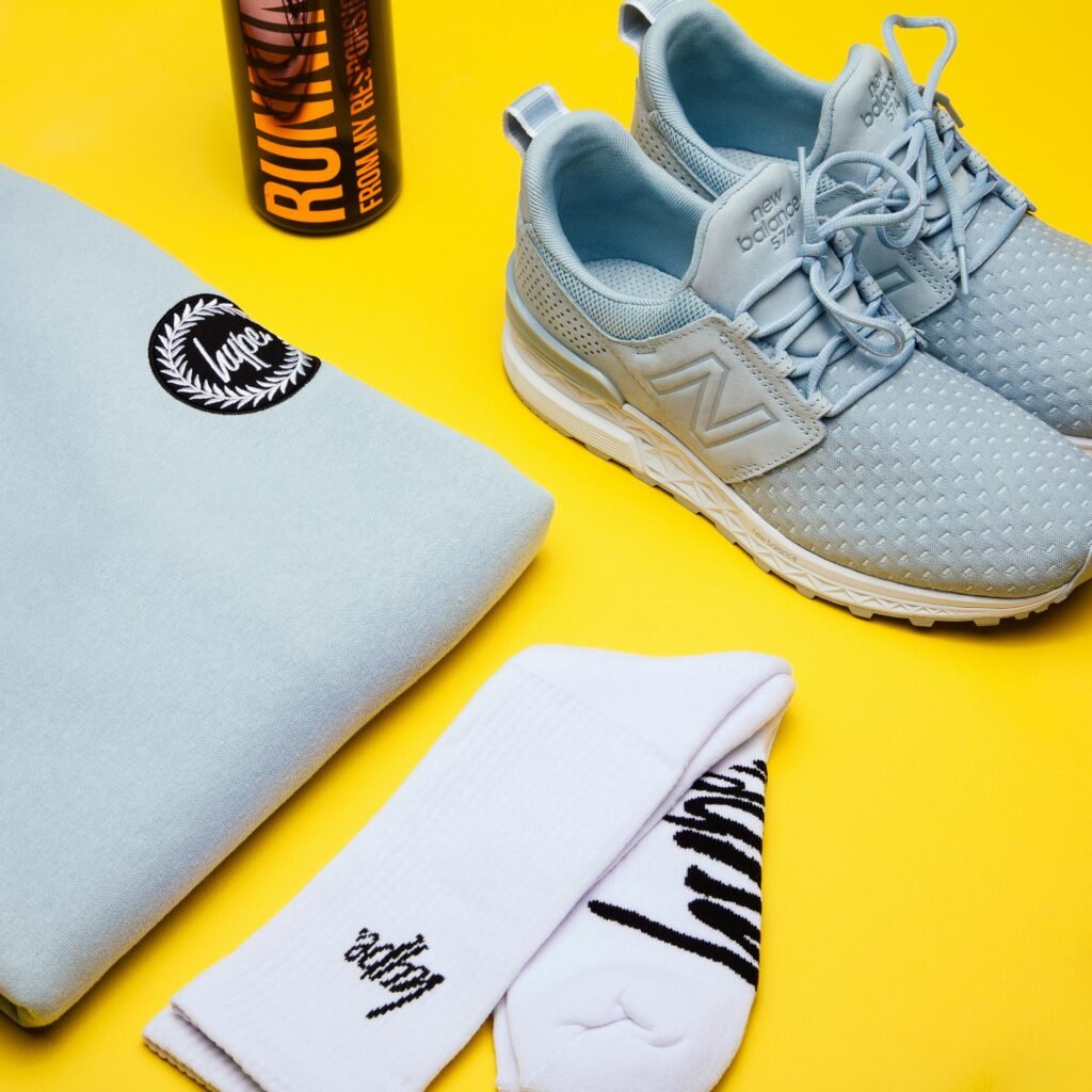 Colorful flat lay of sneakers, hoodie, and socks on a bright yellow background.