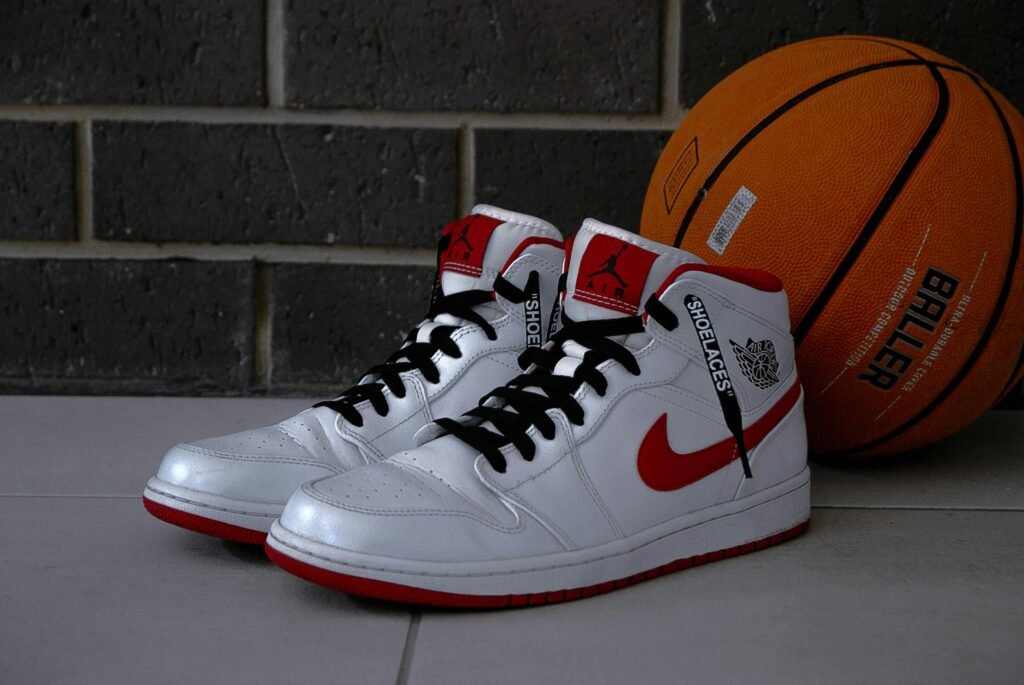 Nike Shoes: Redefining Performance, Style, and Innovation White and red basketball sneakers with an orange basketball on tiled floor.