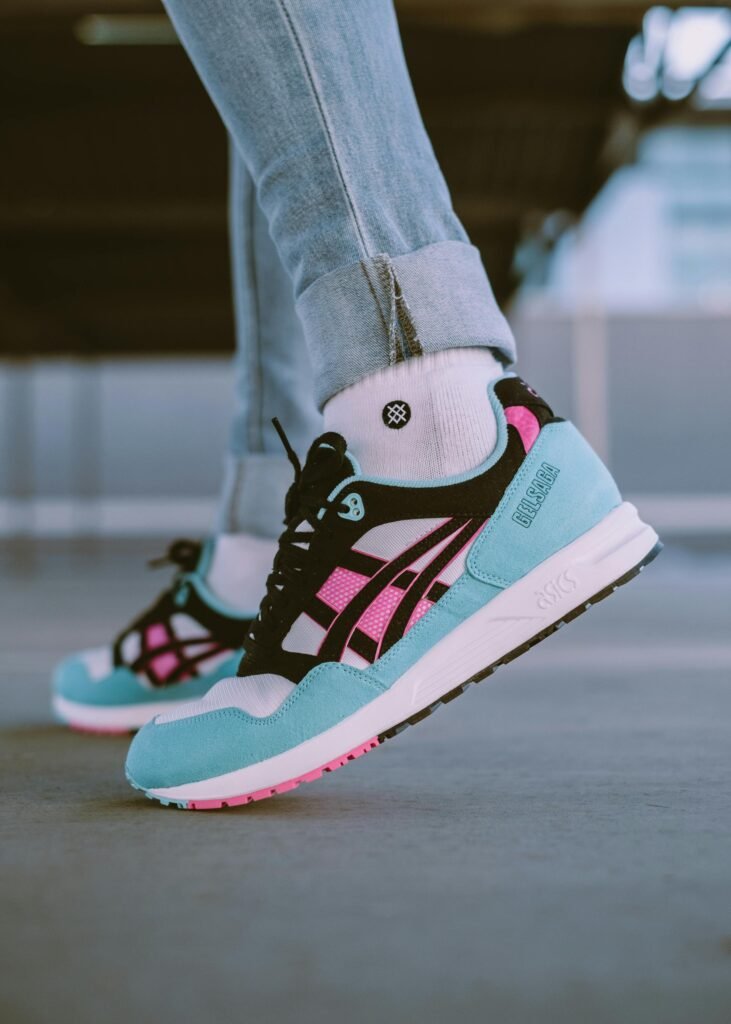 ASICS Shoes: Running Toward Innovation Close-up view of stylish colorful sneakers worn with jeans, captured outdoors.